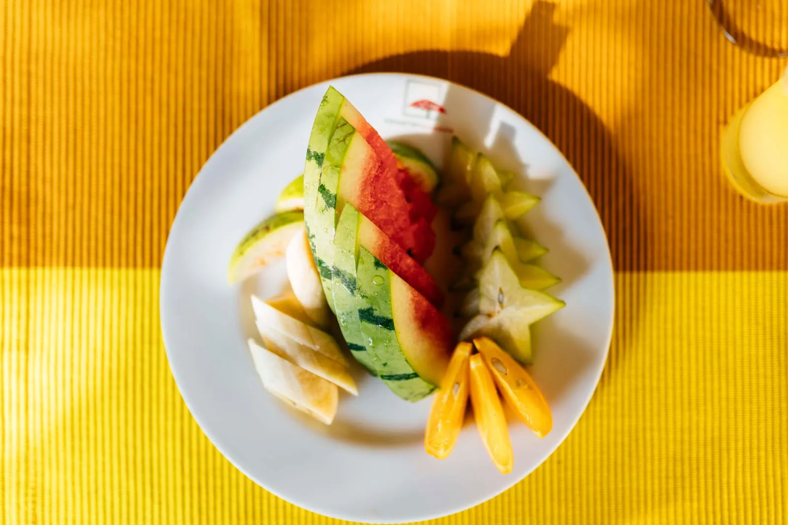 A plate of sliced tropical fruits including star fruit and watermelon