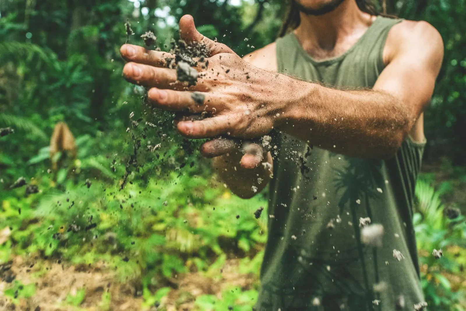 A farm worker's hands with soil, representing sustainable growing practices